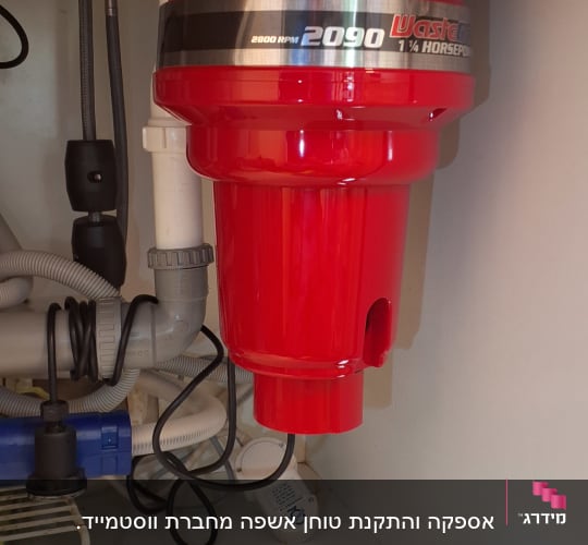 מטחנת אשפה אדומה מותקנת מתחת לכיור במטבח